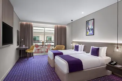 a hotel room with two beds and a table at Leva Hotel and Suites, Opposite Downtown in Dubai