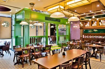 a restaurant with wooden tables and chairs and green walls at Studio One Hotel in Dubai