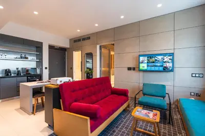 a living room with a red couch and a kitchen at Studio One Hotel in Dubai