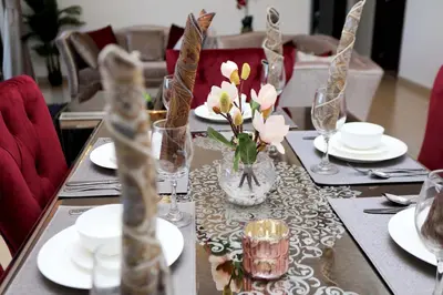 a table with plates and glasses and a vase of flowers at Luxury Casa - Marvel Sea View Apartment JBR Beach 2BR in Dubai