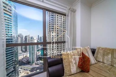 a living room with a couch and a large window at Royal Beach Residence in Dubai