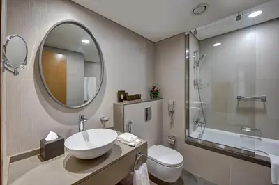 a bathroom with a sink and a toilet and a mirror at The S Hotel Al Barsha in Dubai
