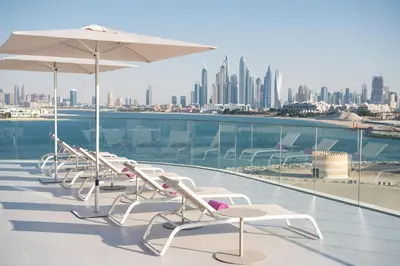 a row of white chairs and umbrellas on a balcony at W Dubai - The Palm in Dubai