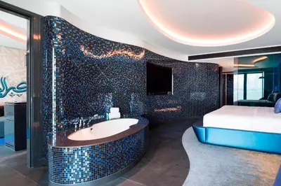 a bathroom with a tub with a bed and a television at W Dubai - The Palm in Dubai