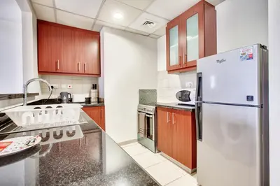a kitchen with a white refrigerator and wooden cabinets at Big Studio in Rimal at The Beach JBR in Dubai