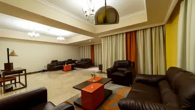 a living room with leather furniture and a piano at Abidos Hotel Apartment Dubai Land in Dubai