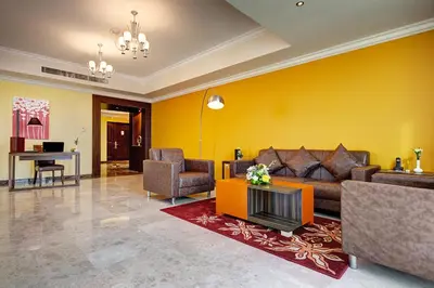 a living room with yellow walls and a couch and chairs at Abidos Hotel Apartment Dubai Land in Dubai
