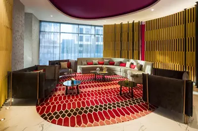 a lobby with a large red carpeted room with couches and tables at Millennium Al Barsha in Dubai