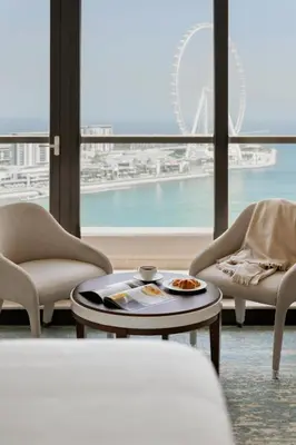 a living room with a table and chairs and a large window at JA Ocean View Hotel, Jumeirah Beach Dubai in Dubai