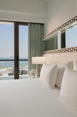 a bedroom with a white bed with a view of the ocean at JA Ocean View Hotel, Jumeirah Beach Dubai in Dubai