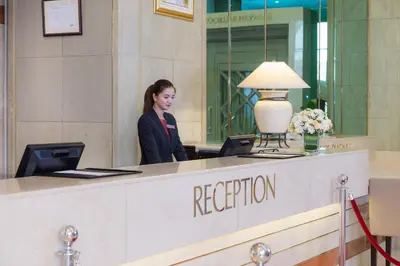 a woman standing at a reception desk in a lobby at Millennium Plaza Downtown Suites in Dubai