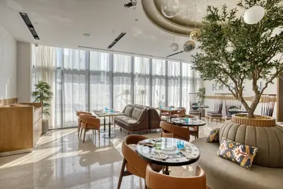 a lobby with tables and chairs and a tree at Millennium Place Dubai Marina in Dubai