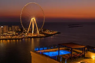 a ferris wheel on top of a building near the water at Jbr penthouse with terrace pool in Dubai