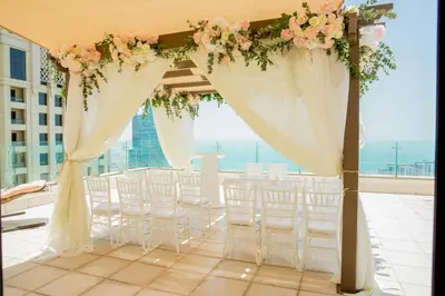 an aisle with white chairs and flowers on a roof at Jbr penthouse with terrace pool in Dubai