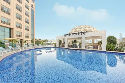 a large swimming pool in a hotel with a building at Barcelo Al Jaddaf, Dubai in Dubai