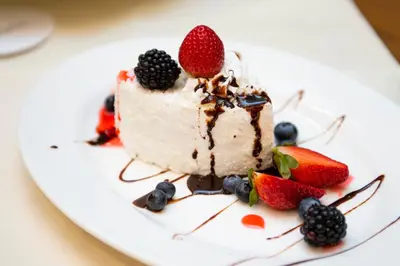 a piece of cake with berries on a white plate at Barcelo Al Jaddaf, Dubai in Dubai