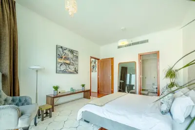 a bedroom with a white bed and a chair at AUBERGE Luxury 2BR Full Burj Khalifa and Fountain View in Dubai