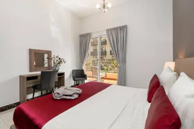 a bedroom with a bed and a desk and a window at BLVD - Spacious Fully Equipped Luxury Residences - Dubai - JVC in Dubai