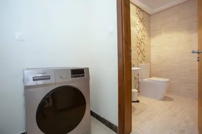 a washing machine in a bathroom with a toilet at BLVD - Spacious Fully Equipped Luxury Residences - Dubai - JVC in Dubai