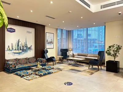 a living room with a couch and a table and chairs at Hampton By Hilton Dubai Al Barsha in Dubai