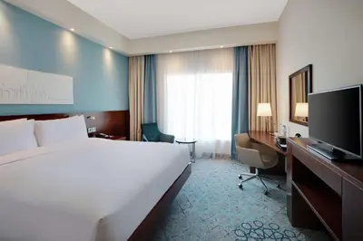 a hotel room with a bed and a desk and a television at Hampton By Hilton Dubai Al Barsha in Dubai