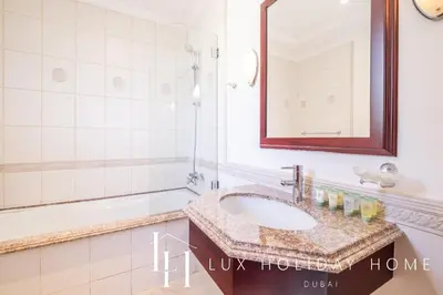a bathroom with a sink and a mirror and a tub at LUX - The Ocean Pearl Villa in Dubai