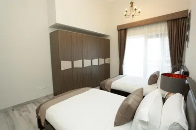 a hotel room with two beds and a window at Marbella Holiday Homes in Dubai