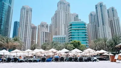 a group of umbrellas and chairs on a beach with buildings at Magic waves holiday in Dubai