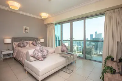 a bedroom with a bed and a couch and windows at Prime Retreats - Downtown Dubai in Dubai