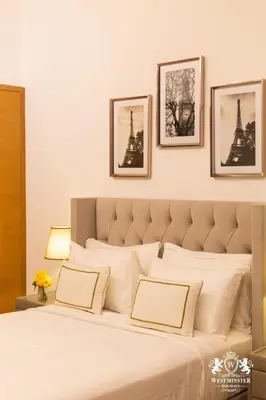 a bedroom with a large white bed with three pictures on the wall at Westminster Claren Tower - Downtown in Dubai