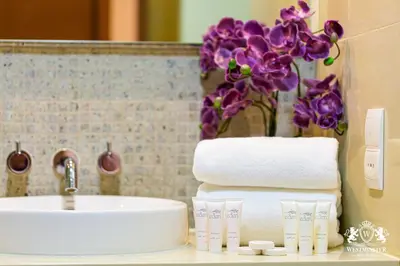 a bathroom sink with towels and a vase of purple orchid at Westminster Claren Tower - Downtown in Dubai