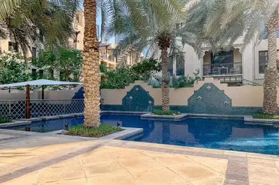 a swimming pool with palm trees in front of a building at Frank Porter - Reehan 5 in Dubai
