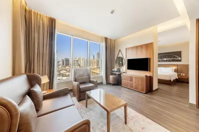 a hotel room with a couch and a bed and a television at Radisson Blu Hotel, Dubai Canal View in Dubai