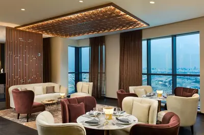 a restaurant with tables and chairs and large windows at Millennium Place Barsha Heights Hotel in Dubai