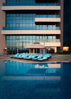 a pool with lounge chairs in front of a building at Millennium Place Barsha Heights Hotel in Dubai