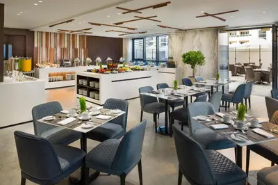 a restaurant with tables and chairs and a kitchen at Millennium Place Barsha Heights Hotel in Dubai