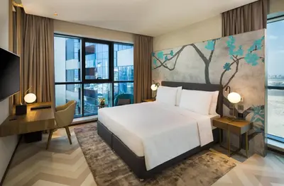 a bedroom with a king sized bed and a desk and a large window at Millennium Place Barsha Heights Hotel Apartments in Dubai