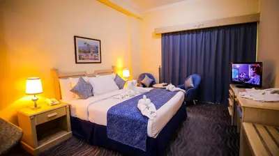 a hotel room with a bed and a tv at Green House Hotel Suites & Apartment in Dubai