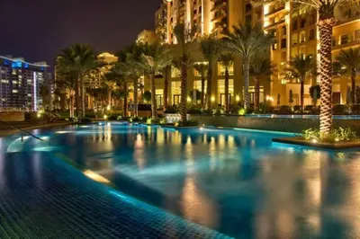 a large pool with palm trees and buildings at night at South & North Residence Palm Jumeirah in Dubai