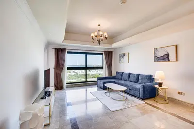 a living room with a blue couch and a large window at South & North Residence Palm Jumeirah in Dubai