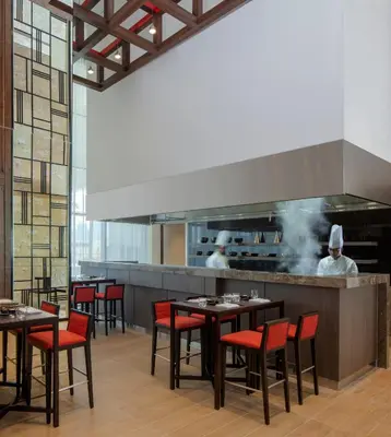a restaurant with tables and chefs in the kitchen at Hyatt Place Dubai Jumeirah Residences in Dubai