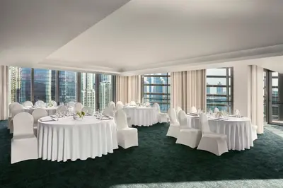 a room with white tables and white chairs and windows at Anantara Downtown Dubai in Dubai