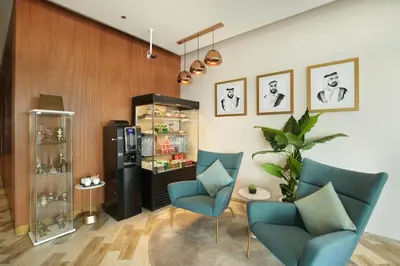 a living room with two blue chairs and a refrigerator at Millennium Executive Apartments Mont Rose in Dubai