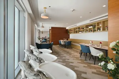a waiting room with white chairs and tables at Millennium Executive Apartments Mont Rose in Dubai