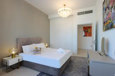 a bedroom with a large white bed and a chandelier at Elite Duplex Penthouse Steps from Metro & Marina in Dubai