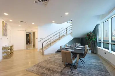 a dining room with a table and chairs and a staircase at Elite Duplex Penthouse Steps from Metro & Marina in Dubai