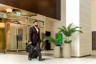 a man in a suit walking in a lobby with a suitcase at Hyatt Place Dubai Jumeirah in Dubai