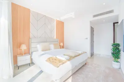 a white bedroom with a bed and a plant at JW Marriott Full Marina View, Luxury Suites by Gardenia with Direct Access to Marina Mall in Dubai