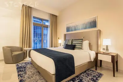 a bedroom with a bed and a chair and a window at Staycae Avanti in Dubai