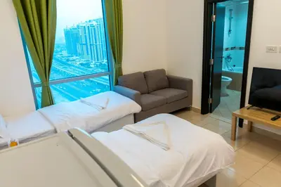 a room with two beds and a couch and a window at La Rivera Rooms for Ladies in Dubai